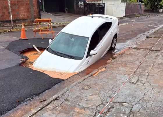 Carro ficou preso em cratera aberta após o asfalto ceder durante chuva forte em Campo Grande - Foto: Giovanna Dauzacker/TV Morena